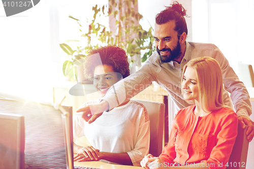 Image of happy creative team with computer in office