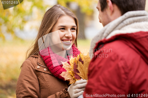 Image of happy couple with maple leaves in autumn park