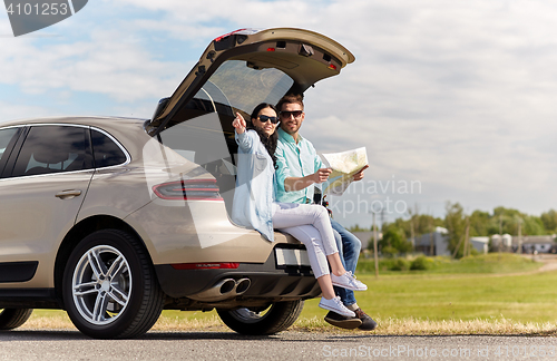 Image of happy man and woman with road map at hatchback car