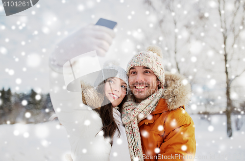 Image of happy couple taking selfie by smartphone in winter