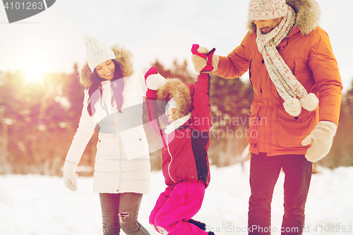 Image of happy family in winter clothes walking outdoors