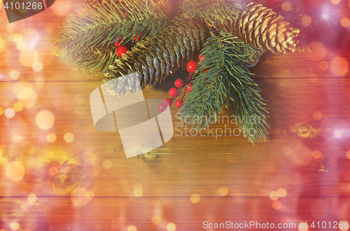 Image of close up of fir branch with cones on wooden table