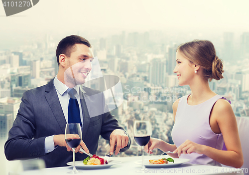 Image of smiling couple eating main course at restaurant