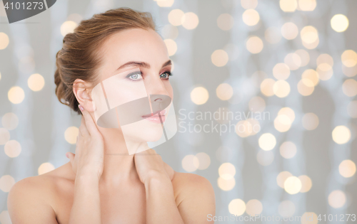 Image of beautiful woman touching her neck over lights