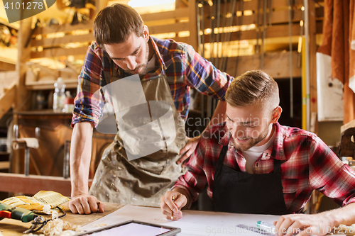 Image of workmen with tablet pc and blueprint at workshop