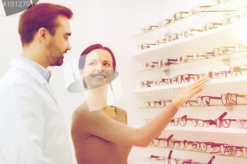 Image of woman showing glasses to optician at optics store