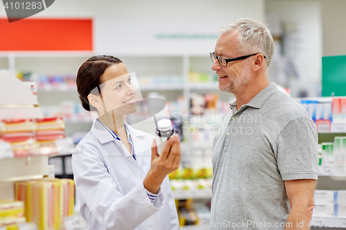 Image of pharmacist showing drug to senior man at pharmacy