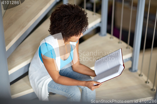 Image of african student girl reading book at library
