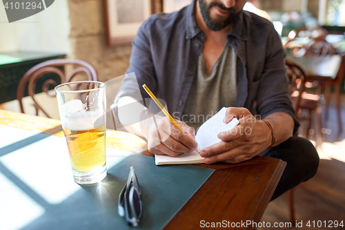 Image of close up of man with beer and notebook at pub
