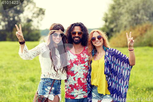 Image of happy young hippie friends showing peace outdoors