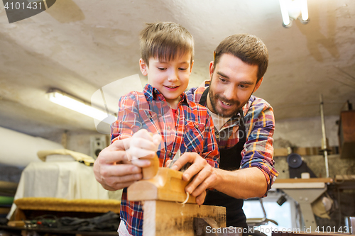 Image of father and son with plane shaving wood at workshop