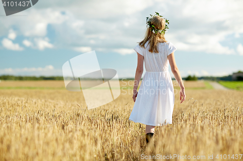 Image of happy young woman in flower wreath on cereal field