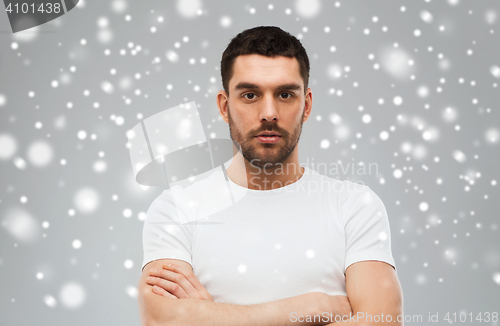 Image of young man with crossed arms over snow background