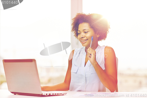 Image of happy african woman with laptop at office