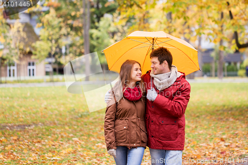 Image of smiling couple with umbrella in autumn park