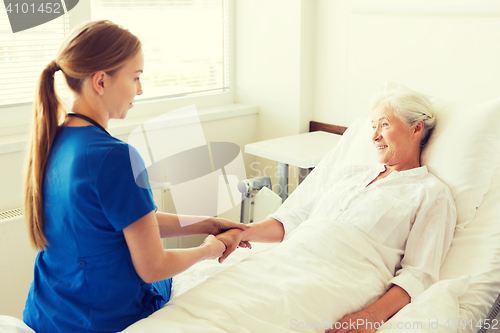 Image of doctor or nurse visiting senior woman at hospital