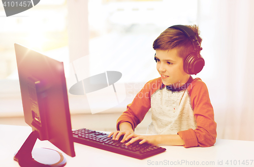 Image of happy boy with computer and headphones at home