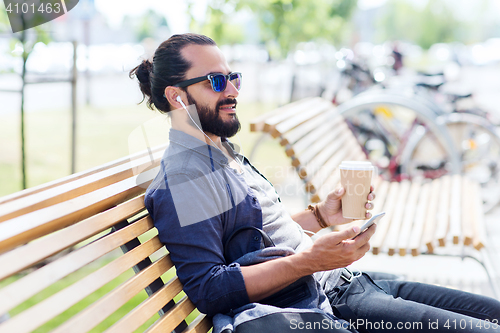 Image of man with earphones and smartphone drinking coffee