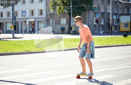 Image of teenage boy on skateboard crossing city crosswalk