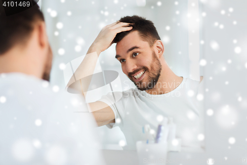 Image of happy young man looking to mirror at home bathroom