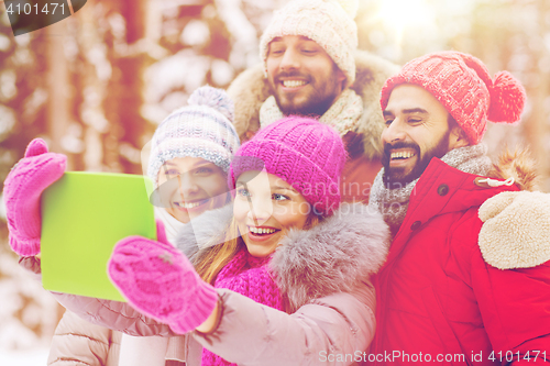 Image of smiling friends with tablet pc in winter forest