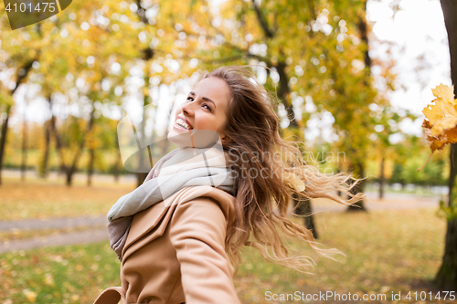 Image of beautiful happy young woman walking in autumn park