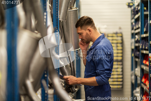 Image of auto mechanic with clipboard at car workshop