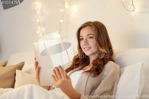 Image of happy young woman with tablet pc in bed at home