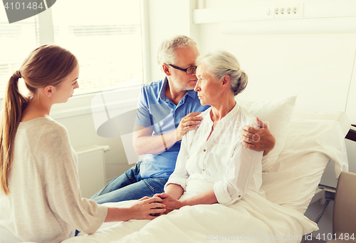 Image of family visiting ill senior woman at hospital