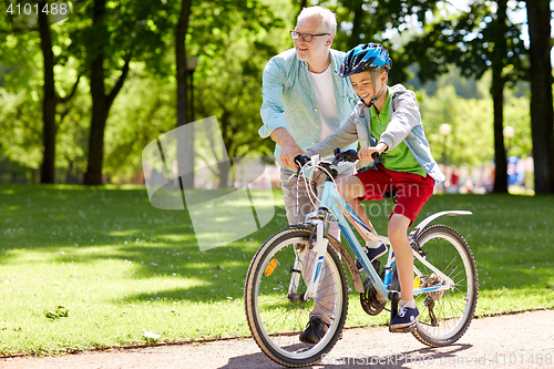 Image of grandfather and boy with bicycle at summer park