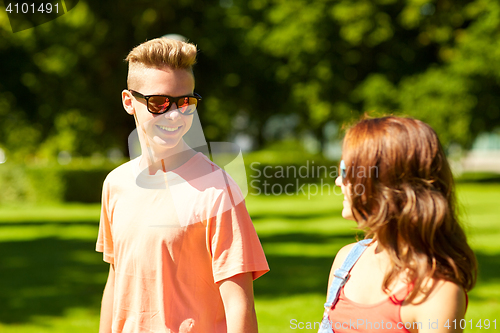 Image of happy teenage couple walking at summer park