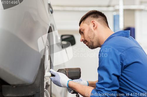 Image of mechanic with screwdriver changing car tire