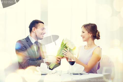 Image of smiling man giving flower bouquet at restaurant