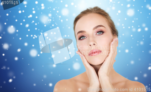 Image of beautiful woman touching her face over snow