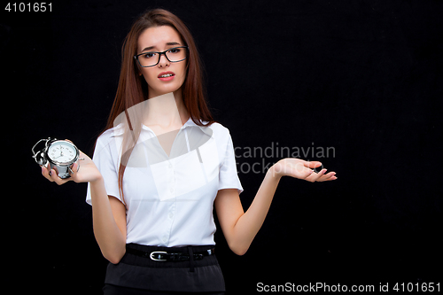 Image of The young business woman with alarm clock on black background