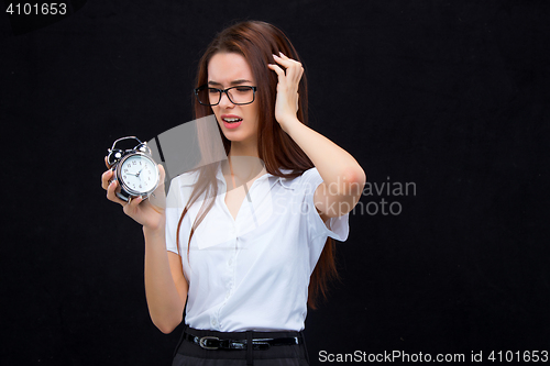 Image of The young business woman with alarm clock on black background