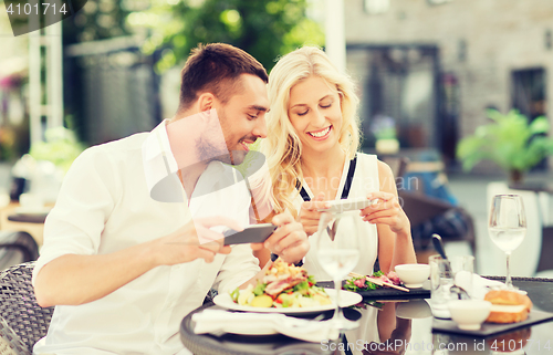 Image of happy couple with smatphone photographing food