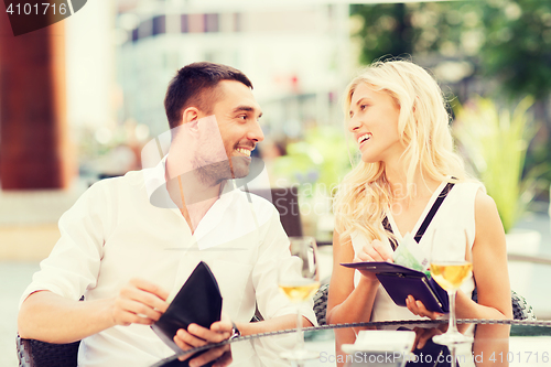 Image of happy couple with wallet paying bill at restaurant