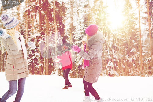 Image of happy friends playing snowball in winter forest