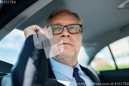 Image of senior businessman calling on smartphone in car