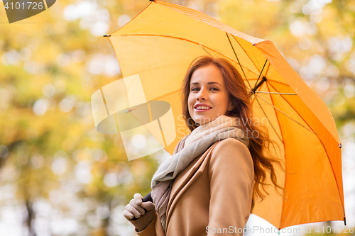 Image of happy woman with umbrella walking in autumn park