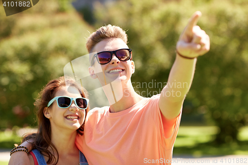 Image of happy couple pointing finger at summer park