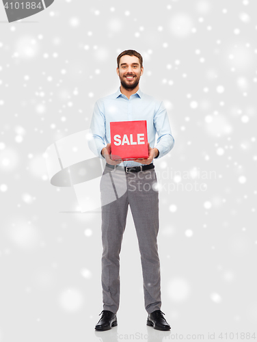 Image of smiling man with red sale sign over snow