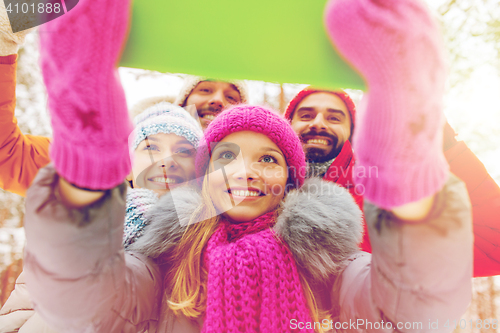 Image of smiling friends with tablet pc in winter forest