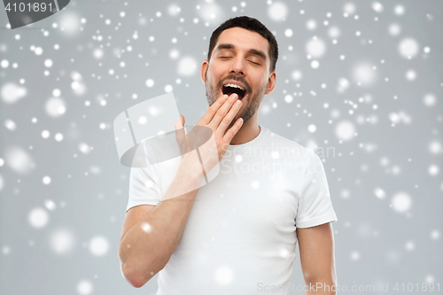 Image of yawning man over snow background