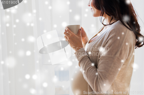 Image of close up of pregnant woman with tea cup at window