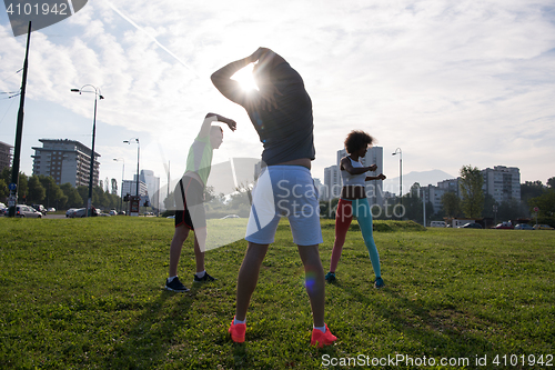 Image of multiethnic group of people stretching in city park