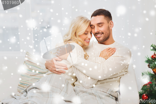 Image of happy couple hugging on sofa at home