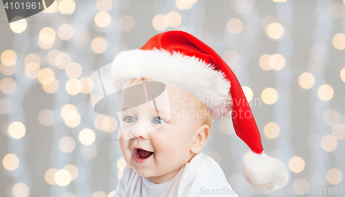 Image of baby boy in christmas santa hat over blue lights