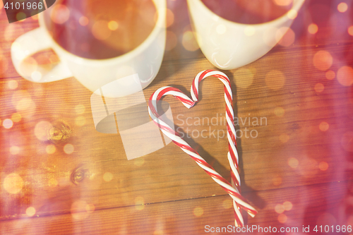 Image of christmas candy canes and cups on wooden table